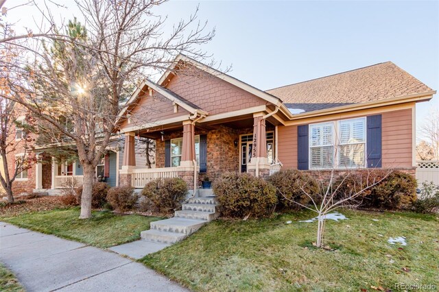 12955 Vallejo Cir, Westminster, CO 80234 - view of front of house with a porch, a front yard, and stone siding