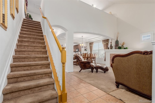 stairway with tile patterned flooring, a high ceiling, and a chandelier