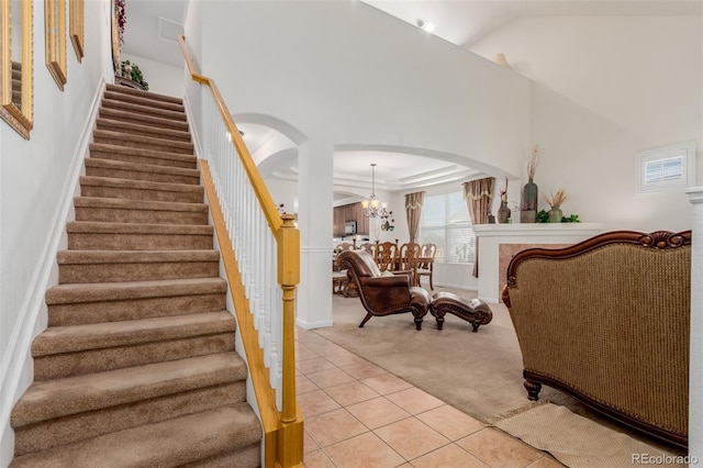 12955 Vallejo Cir, Westminster, CO 80234 - staircase with arched walkways, carpet floors, a chandelier, tile patterned floors, and vaulted ceiling