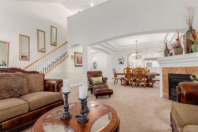 carpeted living room featuring a fireplace, a chandelier, and vaulted ceiling