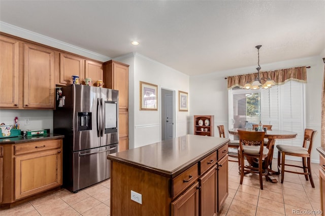 kitchen with hanging light fixtures, crown molding, stainless steel fridge, a notable chandelier, and a kitchen island