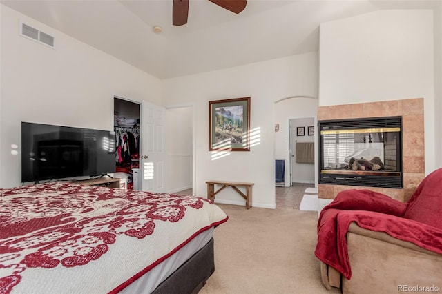 bedroom featuring light carpet, a walk in closet, vaulted ceiling, ceiling fan, and a closet