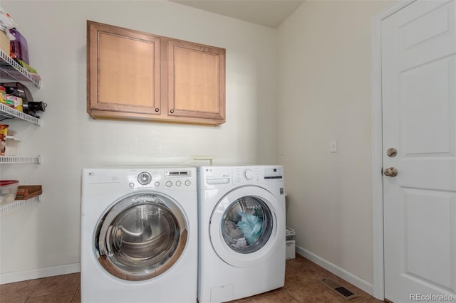 washroom with cabinets, light tile patterned floors, and washing machine and clothes dryer