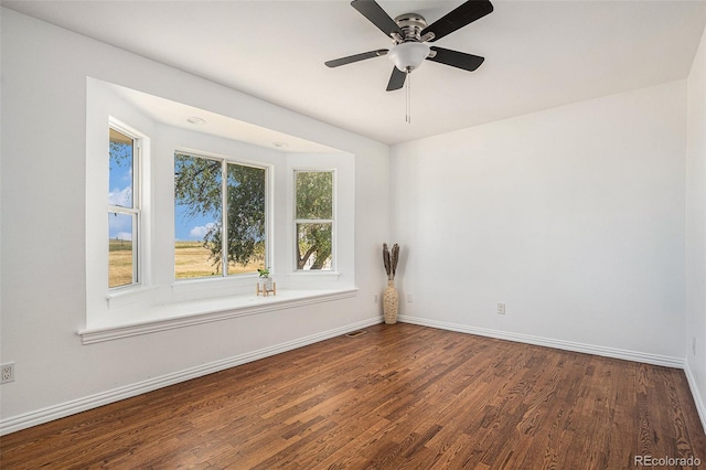 spare room with a ceiling fan, wood finished floors, visible vents, and baseboards