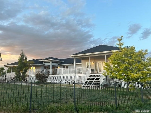 view of front facade with a fenced front yard, a yard, a porch, and stairway