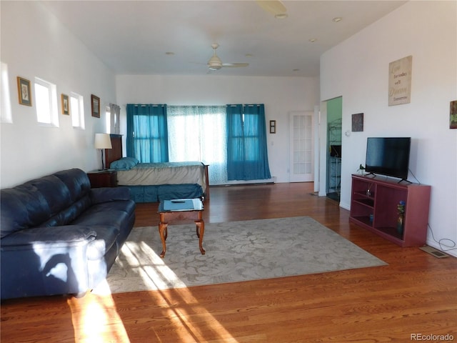 living area featuring visible vents, a ceiling fan, and wood finished floors