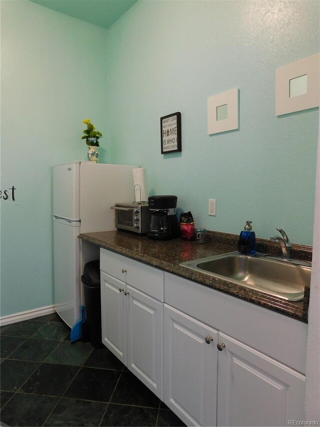 kitchen with dark tile patterned flooring, sink, and white cabinets