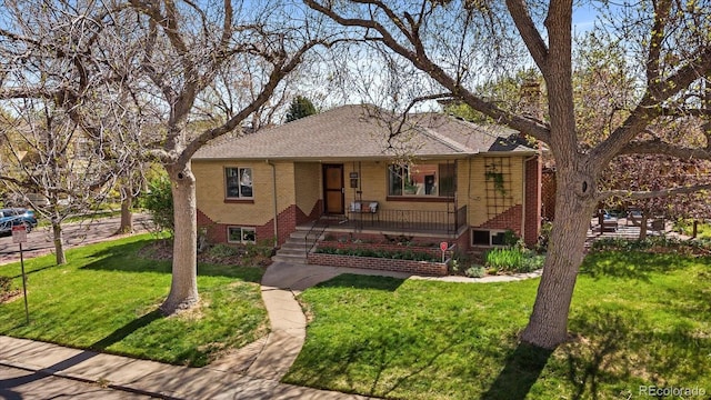 view of front of home featuring brick siding, a front lawn, roof with shingles, and covered porch