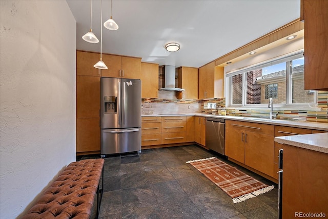 kitchen featuring decorative backsplash, wall chimney range hood, light countertops, a sink, and appliances with stainless steel finishes