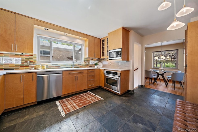 kitchen featuring light countertops, a chandelier, stainless steel appliances, decorative light fixtures, and tasteful backsplash