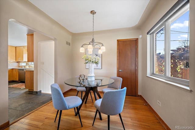 dining area with an inviting chandelier, baseboards, wood finished floors, and visible vents