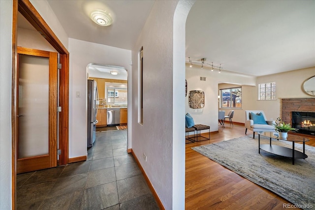 corridor featuring baseboards, arched walkways, visible vents, and track lighting