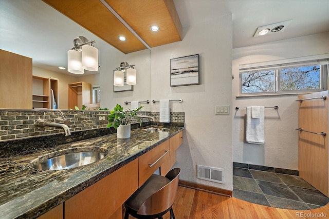 bathroom with double vanity, visible vents, a sink, and tasteful backsplash