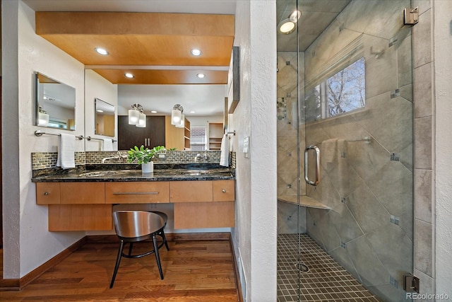 bathroom with double vanity, tasteful backsplash, a shower stall, and wood finished floors