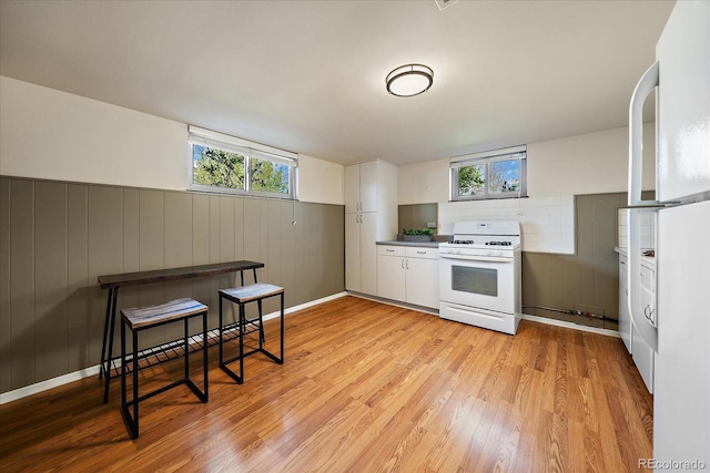 kitchen featuring plenty of natural light, gas range gas stove, light wood-style flooring, and white cabinets