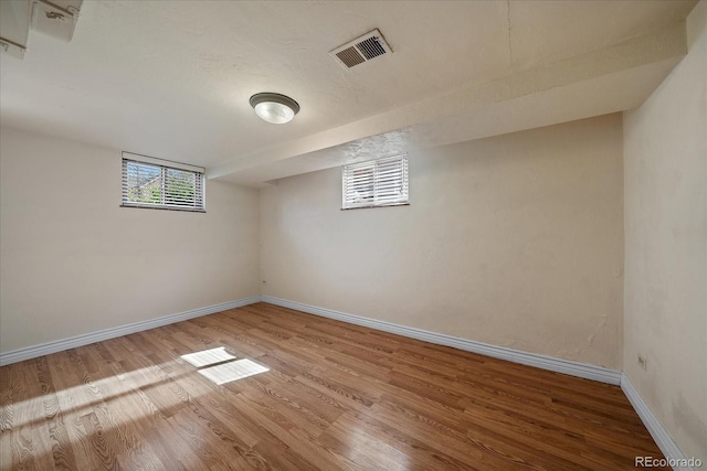 basement with visible vents, baseboards, and wood finished floors