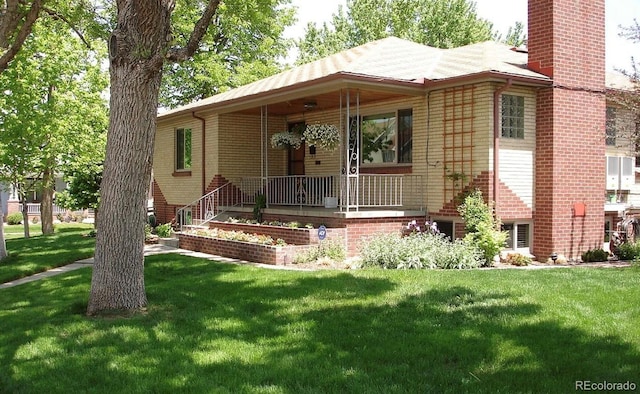 view of front of property with brick siding, a chimney, and a front yard
