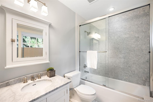 full bathroom featuring vanity, shower / bath combination with glass door, and toilet