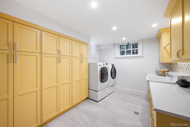 clothes washing area featuring independent washer and dryer, cabinets, and sink