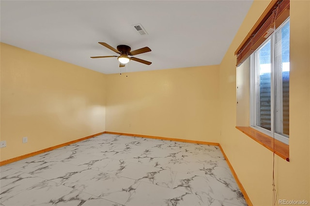 empty room featuring a ceiling fan, marble finish floor, visible vents, and baseboards