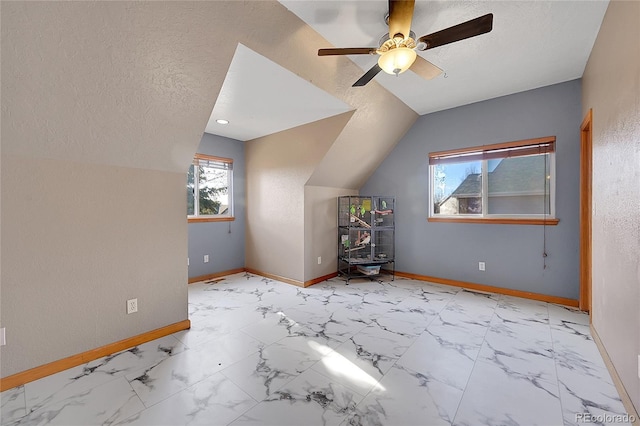 additional living space with a textured ceiling, ceiling fan, lofted ceiling, and baseboards