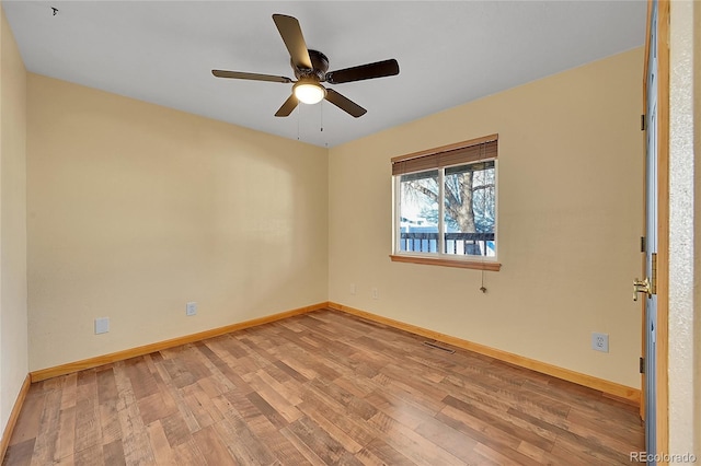 unfurnished room with a ceiling fan, wood finished floors, visible vents, and baseboards