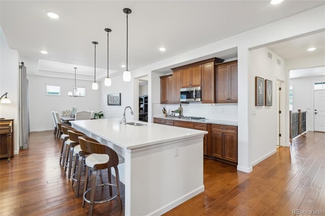15987 E 115th Pl, Commerce City, CO 80022 - kitchen with appliances with stainless steel finishes, a sink, dark wood-style floors, an island with sink, and light countertops