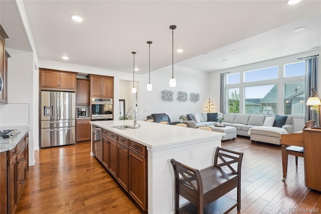 15987 E 115th Pl, Commerce City, CO 80022 - kitchen with appliances with stainless steel finishes, a sink, brown cabinetry, light countertops, and wood finished floors