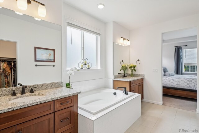 15987 E 115th Pl, Commerce City, CO 80022 - bathroom featuring two vanities, a garden tub, a spacious closet, and baseboards