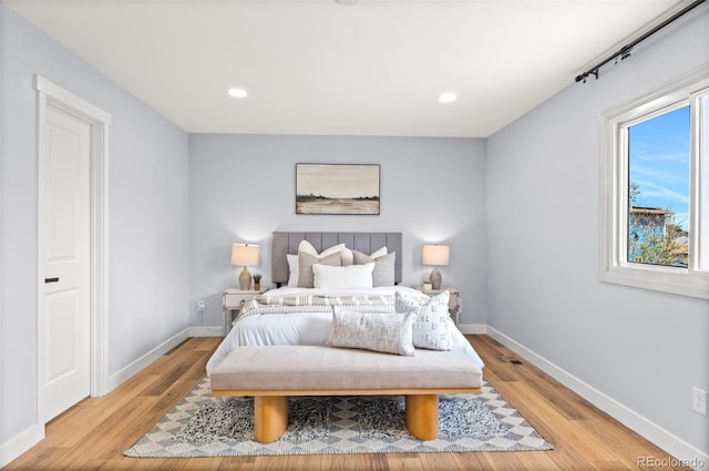 bedroom featuring baseboards, multiple windows, and light wood-style floors