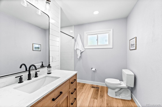 full bath with toilet, wood finished floors, visible vents, baseboards, and vanity