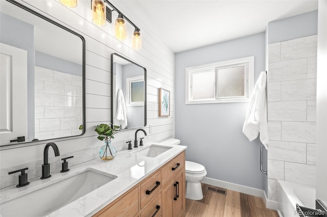 bathroom with a sink, toilet, visible vents, and wood finished floors