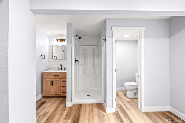 full bathroom with vanity, baseboards, wood finished floors, and a shower stall