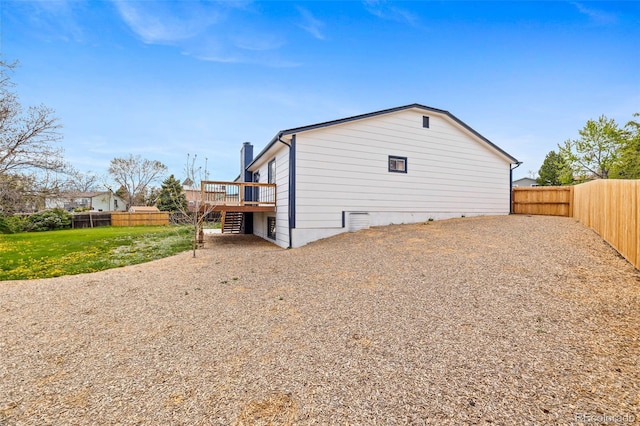 view of home's exterior featuring a chimney, a deck, and a fenced backyard