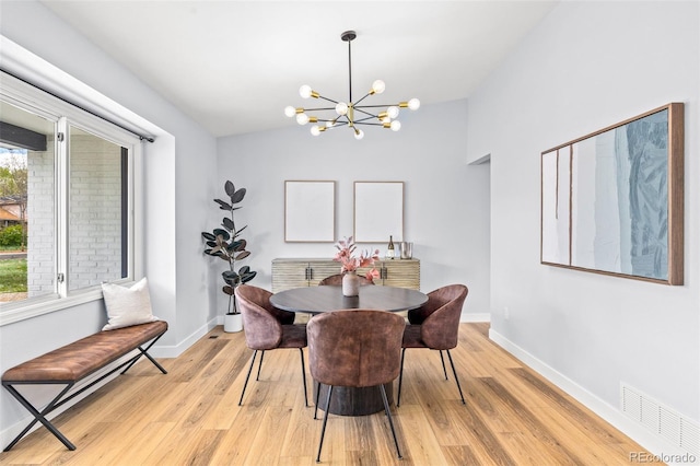 dining space with a chandelier, light wood-type flooring, baseboards, and lofted ceiling