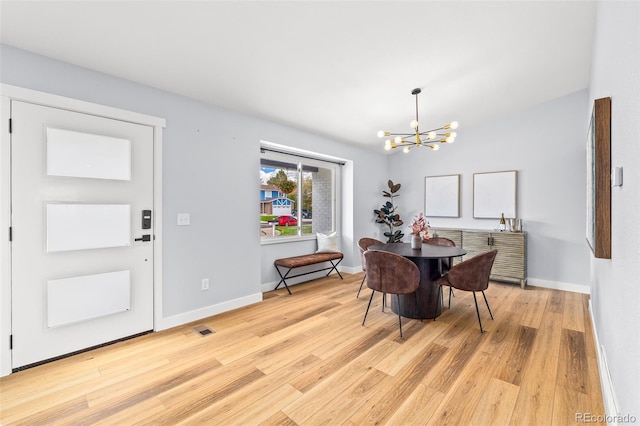 dining space featuring a chandelier, light wood finished floors, and baseboards