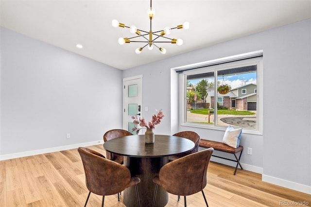 dining space featuring light wood-type flooring, a chandelier, and baseboards