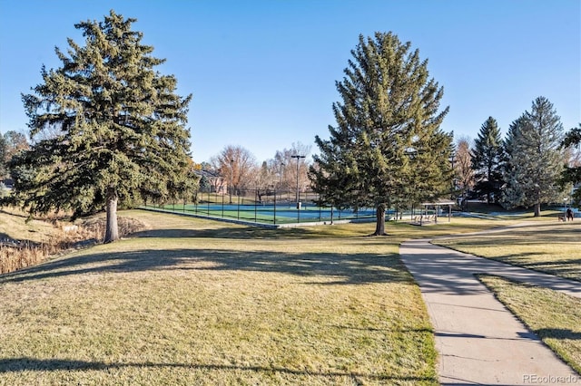 view of home's community featuring tennis court and a lawn