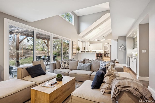 living room with lofted ceiling, a notable chandelier, and light hardwood / wood-style flooring