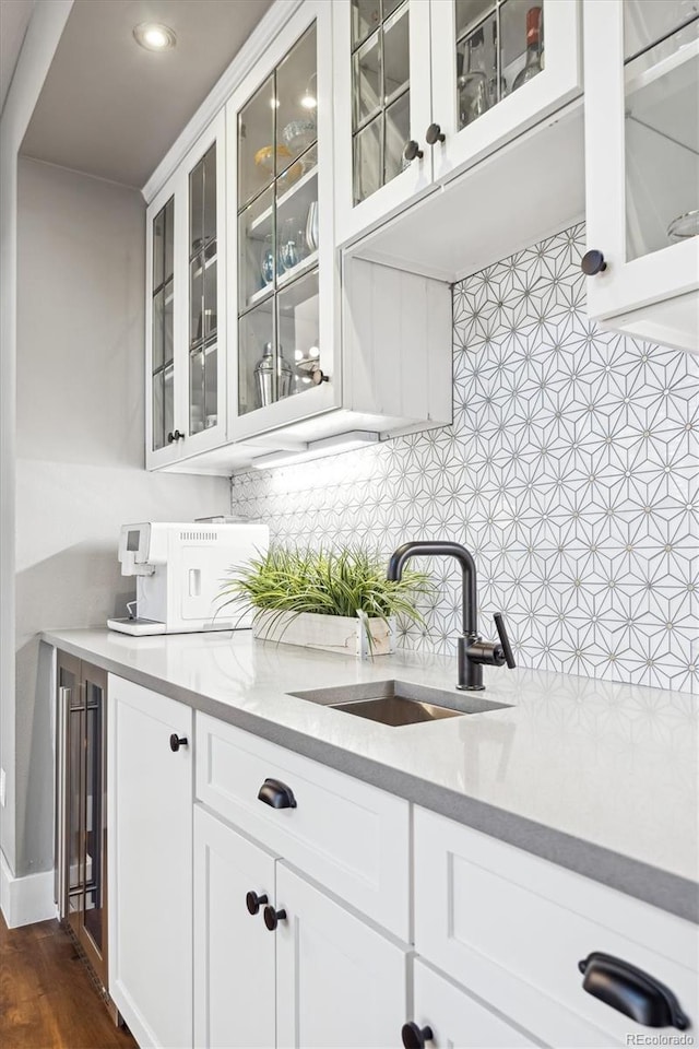 bar with white cabinetry, dark wood-type flooring, sink, and backsplash