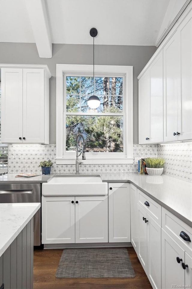 kitchen with hanging light fixtures, a sink, light countertops, white cabinetry, and backsplash