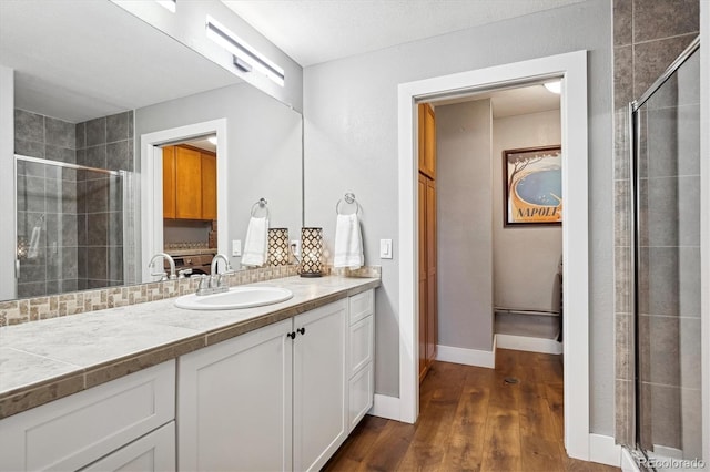 bathroom with a shower stall, baseboards, wood finished floors, and vanity