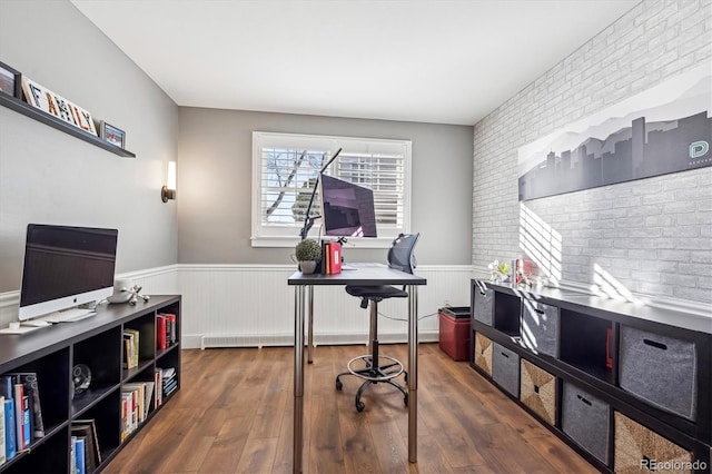 office area featuring brick wall, dark wood-style flooring, and wainscoting