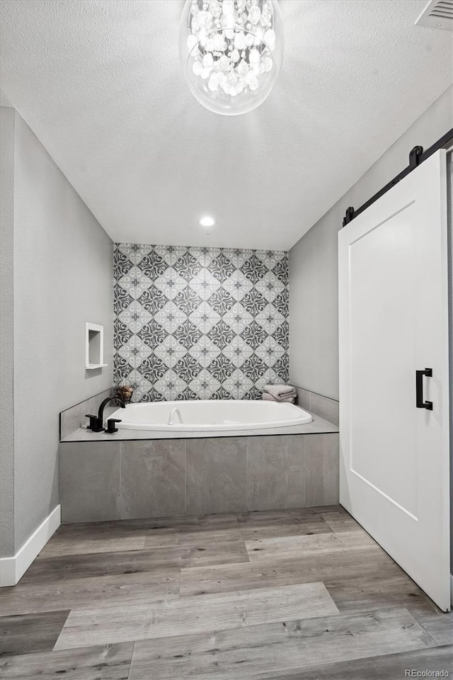 full bath featuring a textured ceiling, visible vents, wood finished floors, and a garden tub