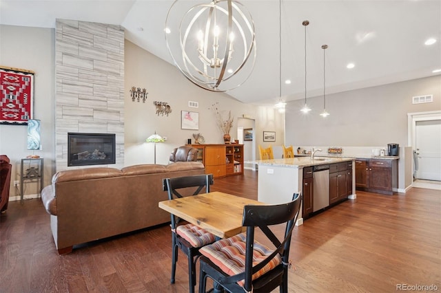 5795 Xenon Way, Arvada, CO 80002 - dining room with dark wood-style floors, a chandelier, high vaulted ceiling, recessed lighting, and a tiled fireplace