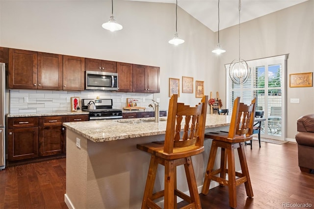 5795 Xenon Way, Arvada, CO 80002 - kitchen featuring stainless steel appliances, high vaulted ceiling, dark wood-style floors, a chandelier, and decorative backsplash