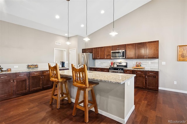 5795 Xenon Way, Arvada, CO 80002 - kitchen with stainless steel appliances, high vaulted ceiling, tasteful backsplash, dark wood finished floors, and an island with sink