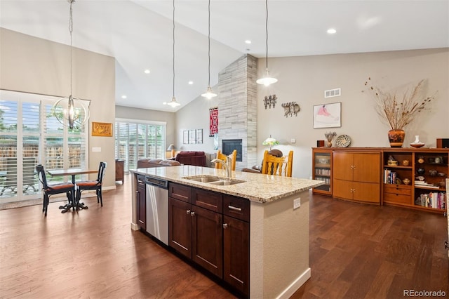 5795 Xenon Way, Arvada, CO 80002 - kitchen with stainless steel dishwasher, high vaulted ceiling, dark wood-type flooring, a large fireplace, and an island with sink
