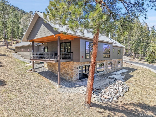 96 Garnet Ln, Pine, CO 80470 - back of house featuring stone siding, a balcony, and a patio area