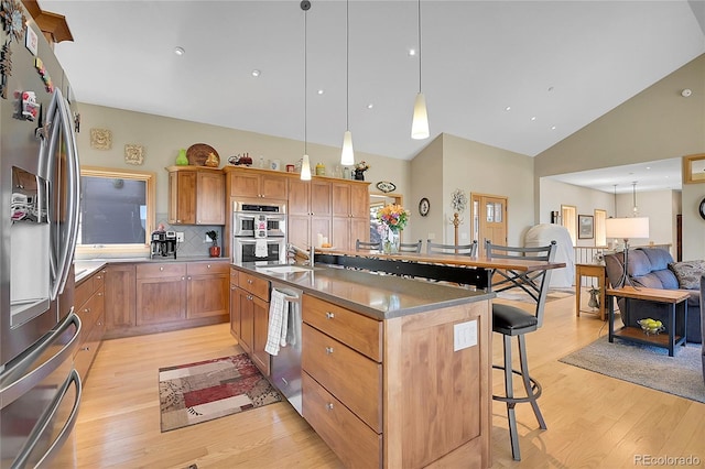 96 Garnet Ln, Pine, CO 80470 - kitchen with stainless steel appliances, a breakfast bar area, light wood-type flooring, high vaulted ceiling, and open floor plan